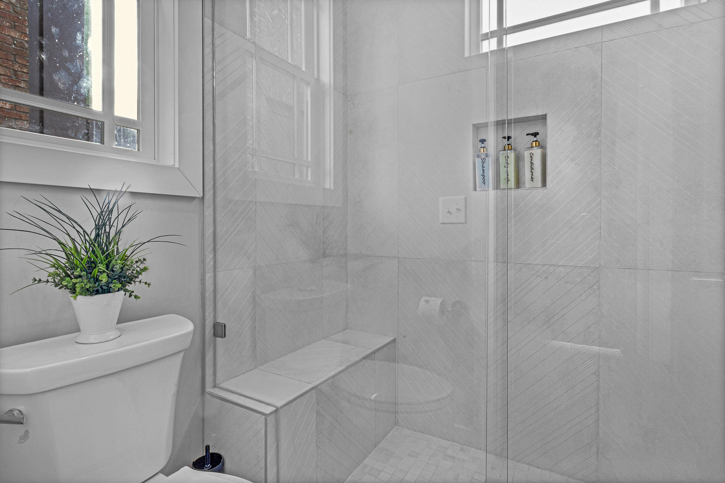 Modern bathroom with tiled shower, toilet, and plant