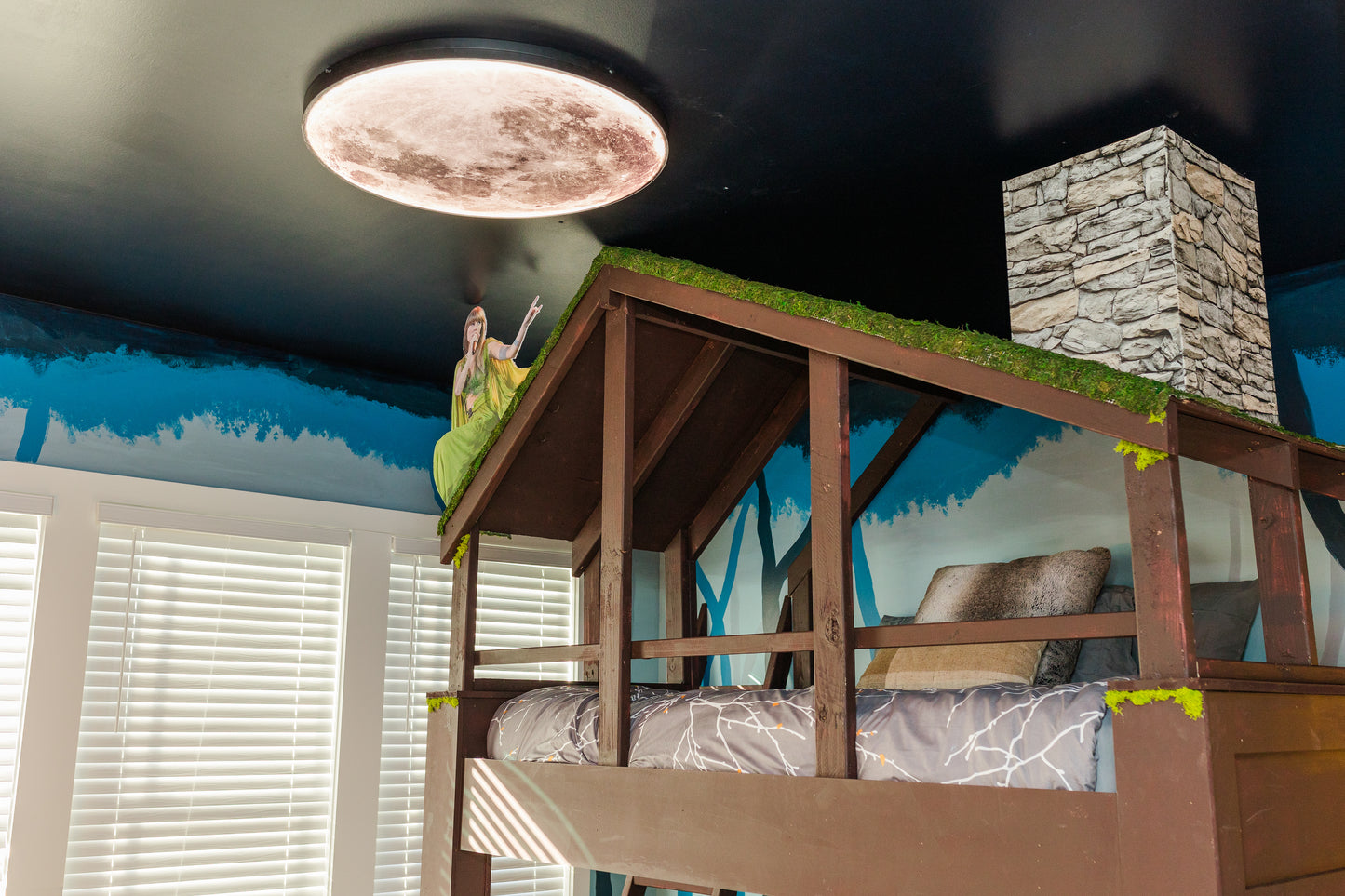 Children's bedroom with a playhouse bed and mural on the wall.