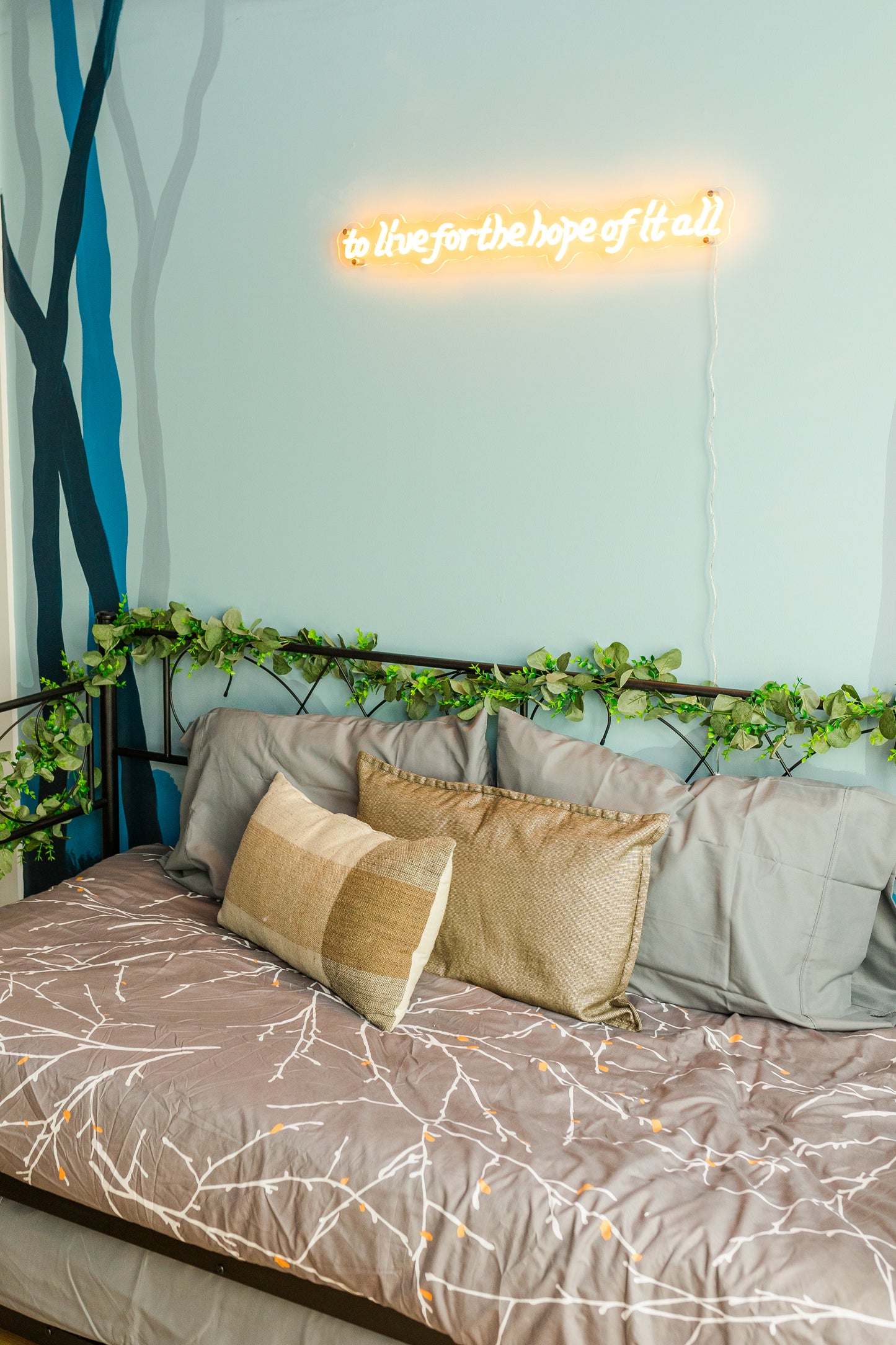 Neon sign above a bed with decorative pillows and bedding