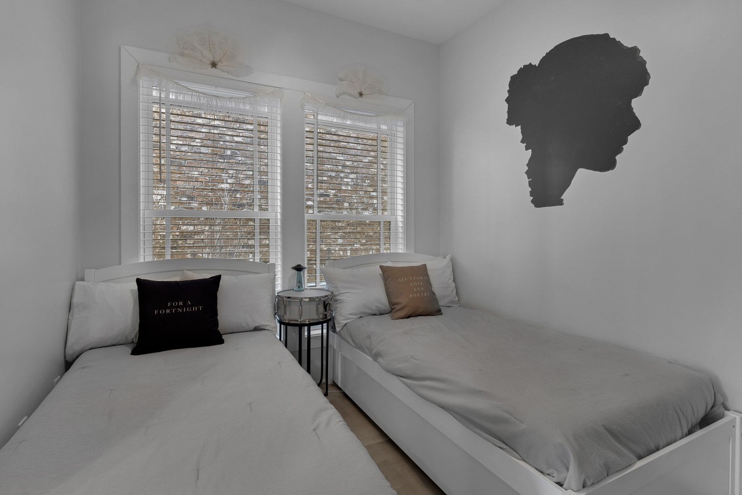 Small bedroom with two beds, a nightstand, and decorative wall art.