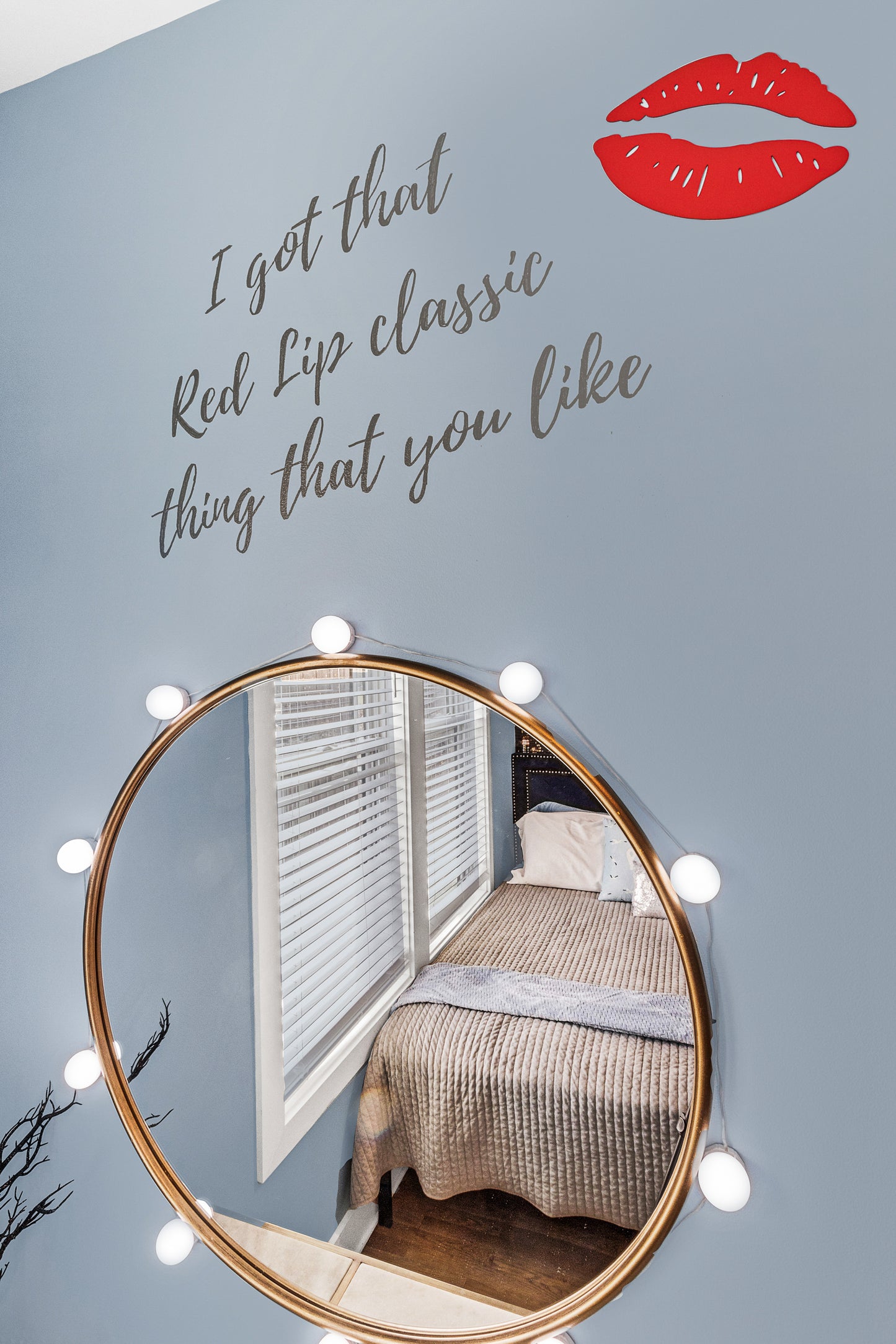 Room interior with a round mirror, bed, and text on the wall.
