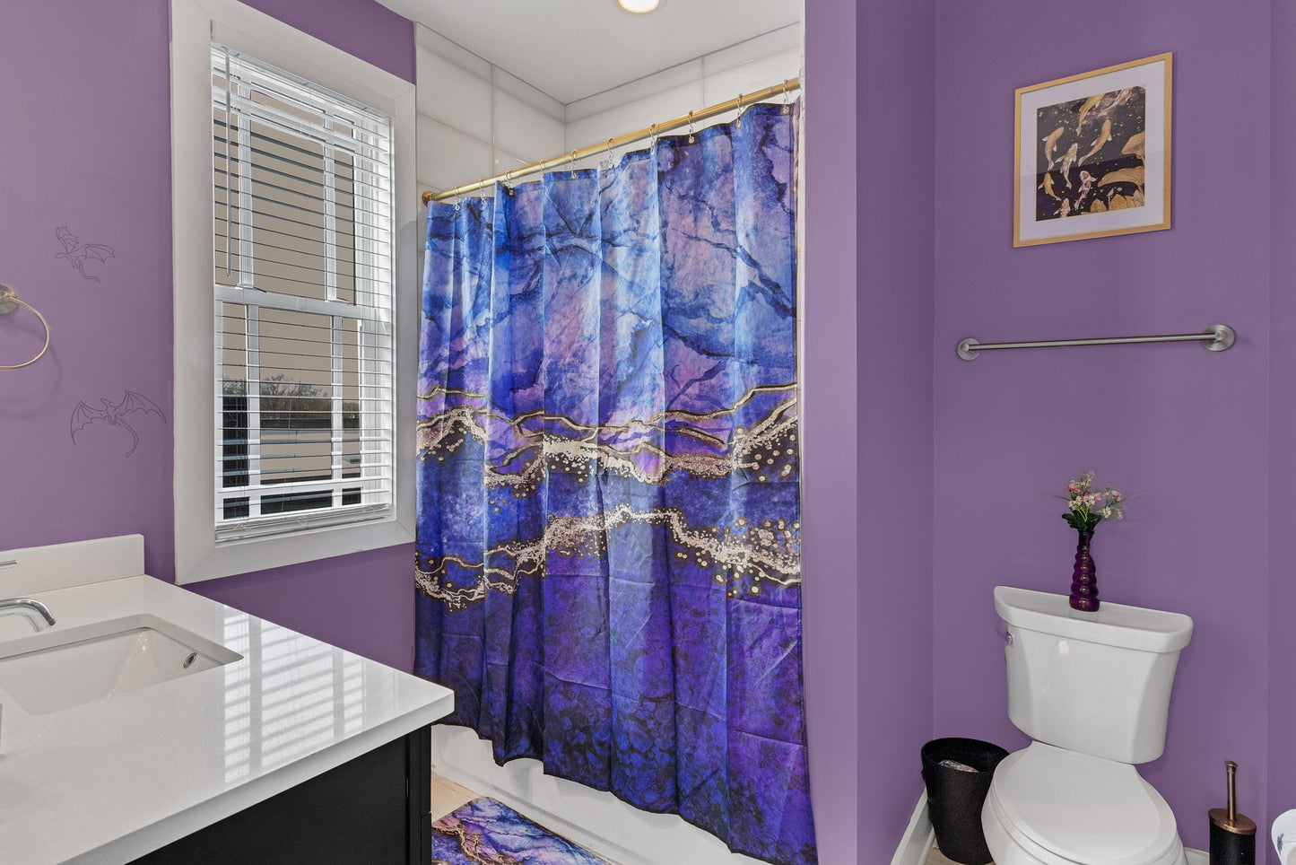 Bathroom with purple walls, a blue patterned shower curtain, and white fixtures.