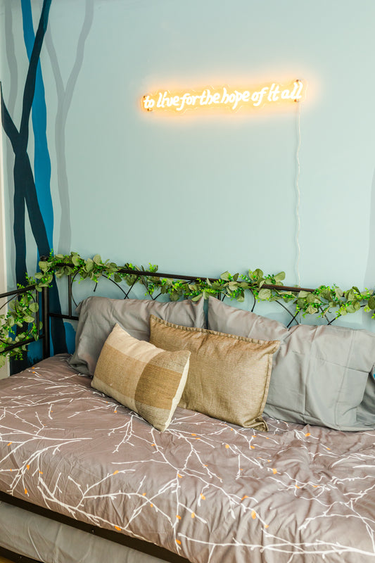 Neon sign above a bed with decorative pillows and bedding