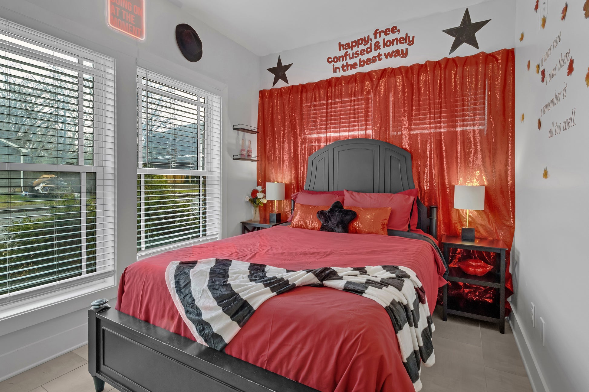 Bedroom with red bedding, black headboard, and decorative wall text.