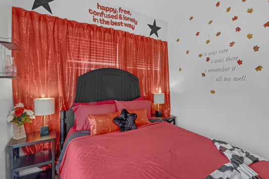 Bedroom with red bedding, red curtains, and wall text.