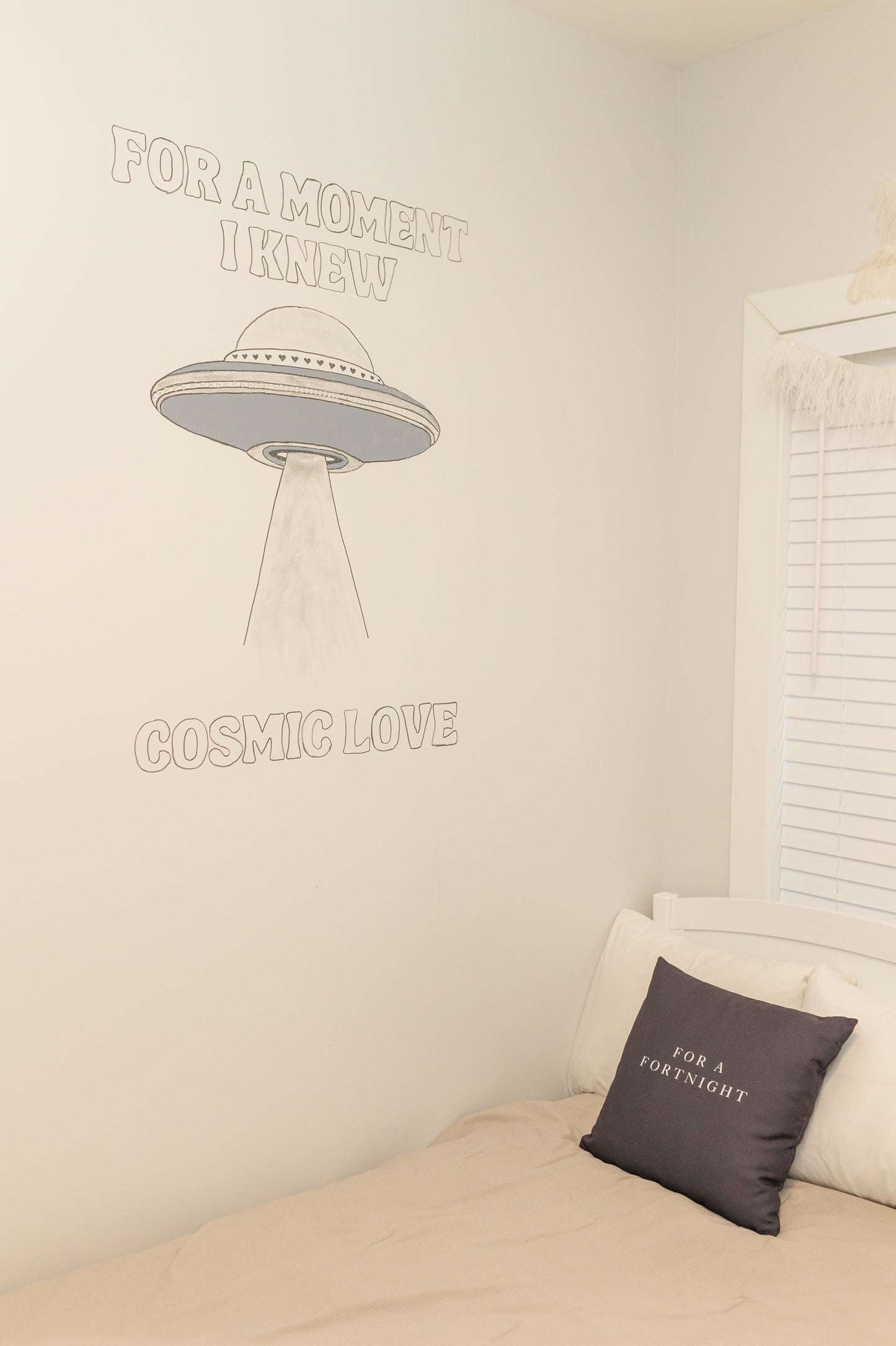 Room interior with a bed and wall text, featuring a UFO illustration.