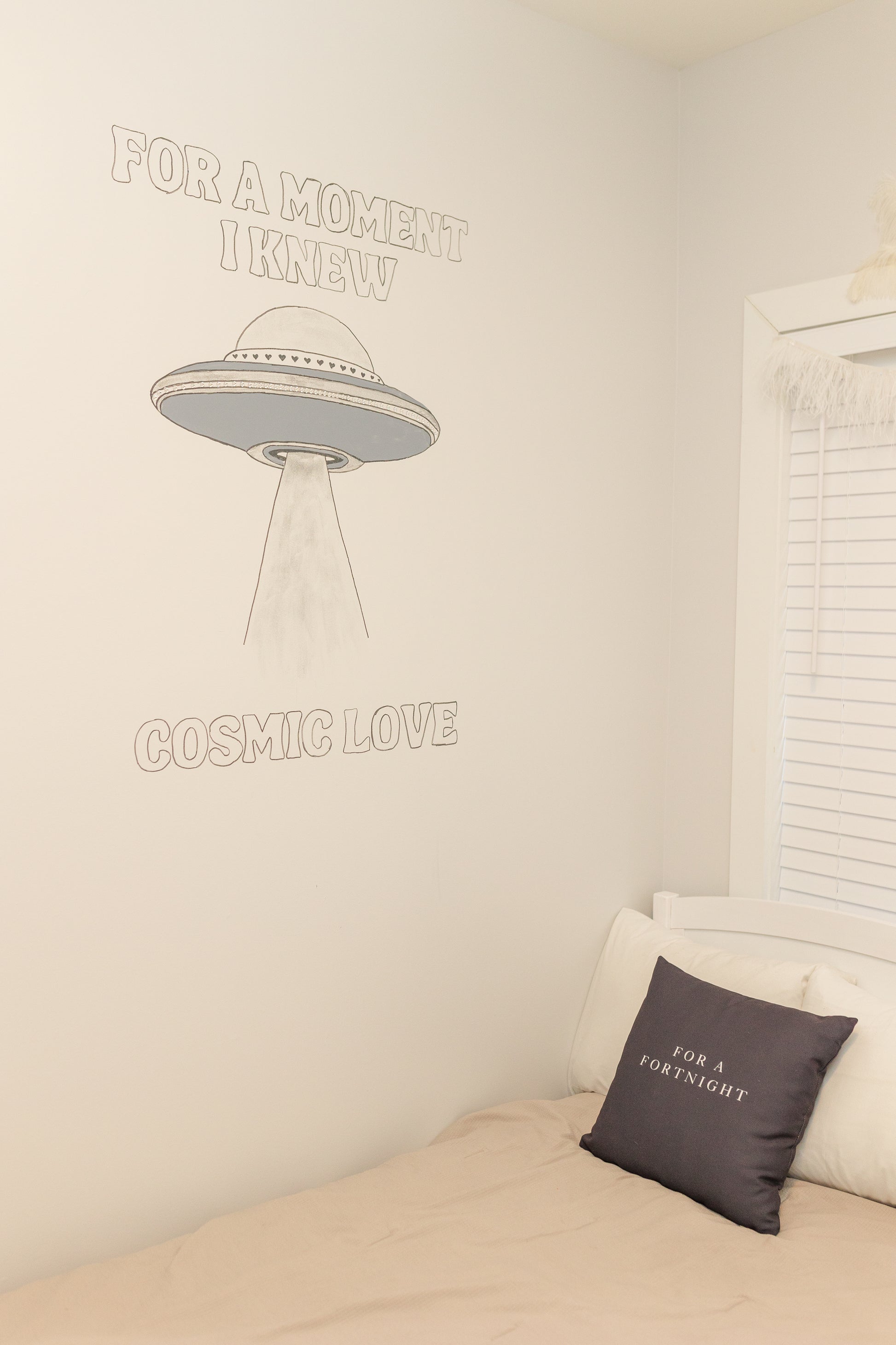 Room interior with a bed and wall text, featuring a UFO illustration.