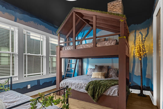Children's bedroom with a wooden bunk bed against a blue wall with tree designs.