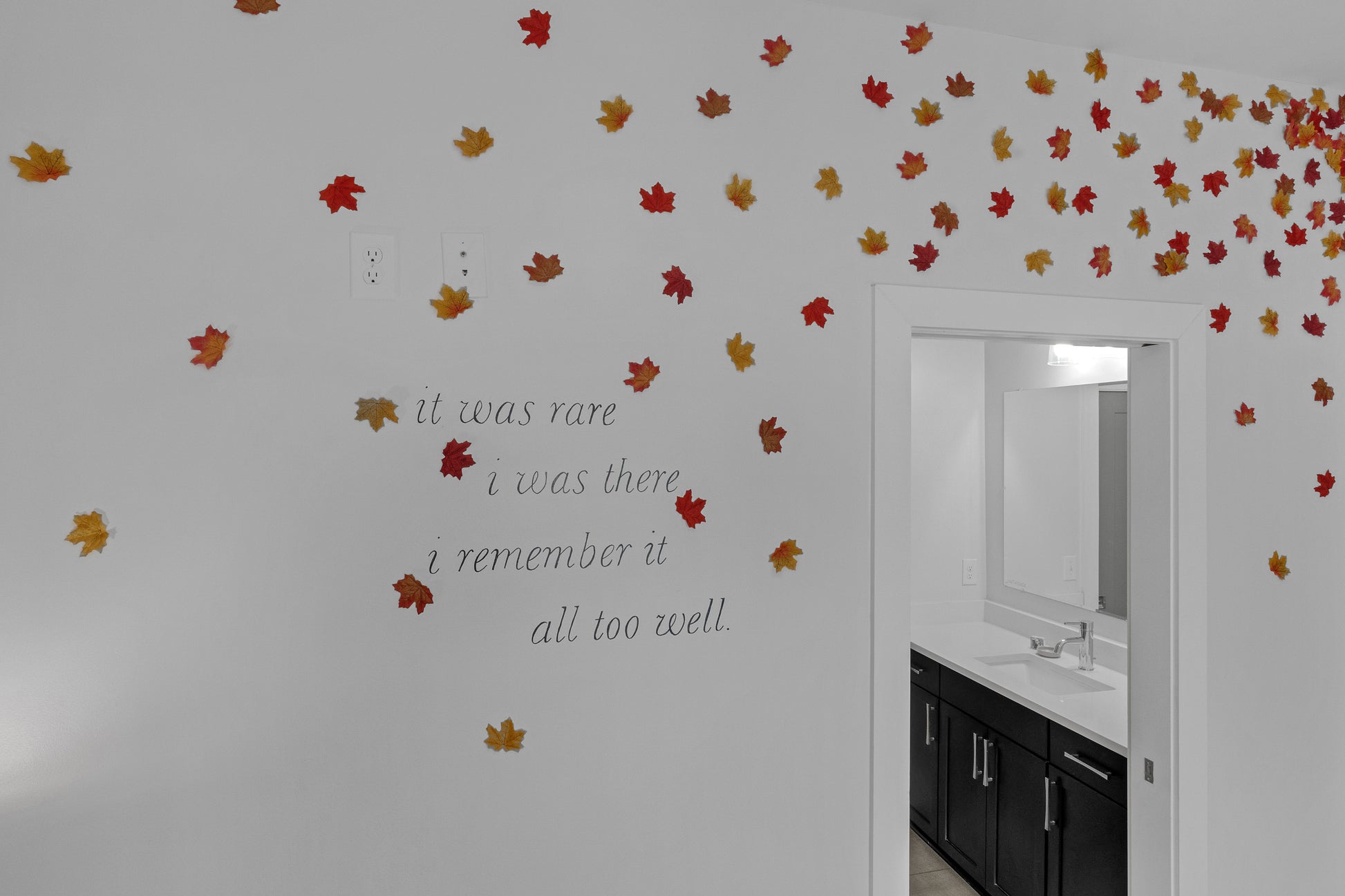 Bathroom with autumn leaf decorations on the wall and a quote.